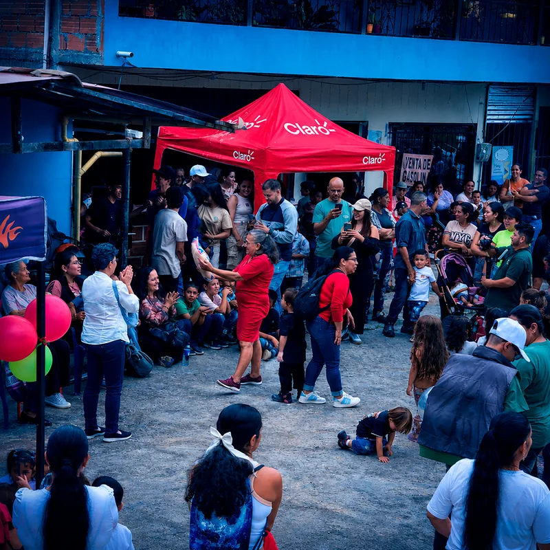 Vista amplia de un evento comunitario bajo carpa con familias del barrio.